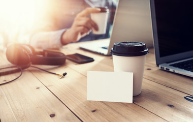 Fototapeta na wymiar White Empty Business Card Mockup Wood Table Take Away Coffee Cup.Adult Businessman Work Modern Notebook Office Blurred Background.Clean Object Ready Private Corporate Information.Horizontal Mock Up.