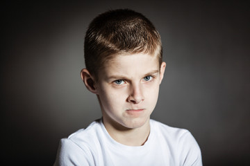 Angry male child posing pensively in dark room