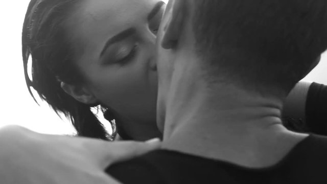 Black and white close-up video of romantic kiss between couple over sky background