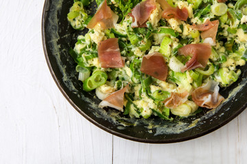 scrambled eggs with green onions and prosciutto in a black iron