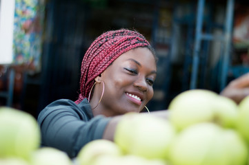 Fototapeta premium smiling young woman choosing apple at street market.