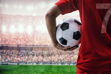 voetbalvoetballer in rood teamconcept dat voetbal in het stadion houdt