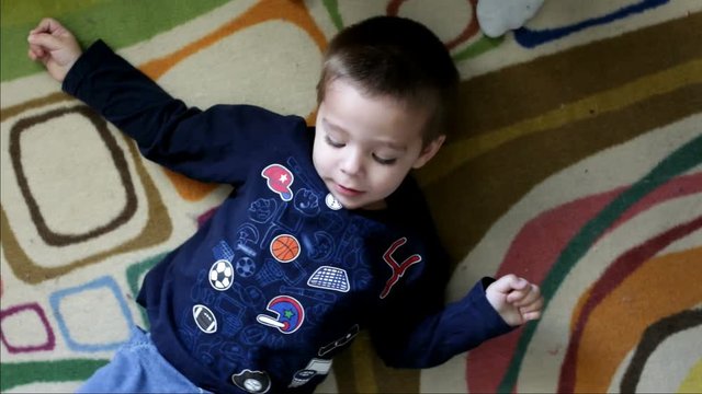 Child laying on ground tickled by foot.