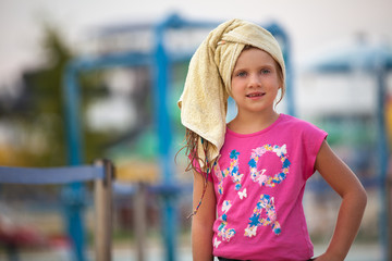 young girl with wet hair, aqua park in the background blured