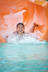 Funny excited child enjoying summer vacation in water park