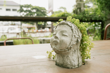 flower pot made of cement as doll of kid with tree in it in garden