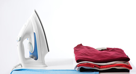 ironing, clothes, housework and objects concept - close up of iron and clothes on table