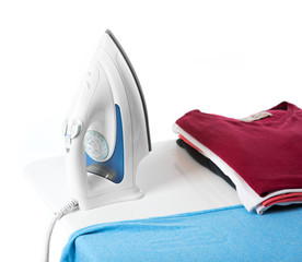 ironing, clothes, housework and objects concept - close up of iron and clothes on table