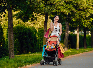 Woman With Baby Carriage Using Cell Phone In Park