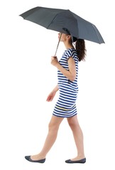 young woman in dress walking under an umbrella. Swarthy girl in a checkered dress comes in the rain.