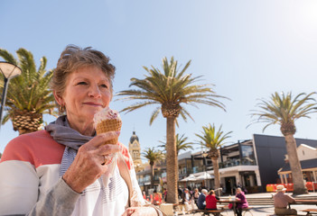 Senior lady eating ice cream at beachside