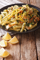 Penne pasta with grilled chicken, fresh herbs and lemon zest close-up. vertical
