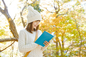 紅葉の中で読書する女性