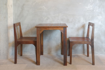 Wooden table and chair in cafe with rough concrete wall in background