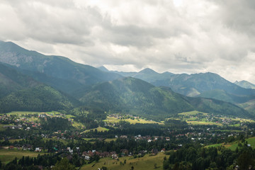 Fototapeta na wymiar View over green valley, village and mountains. Zakopane, Tatry mountains, Poland
