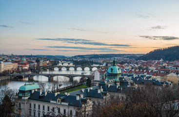 Prague bridges, Vltava river, city sunset panorama red rooftops and multi-coloured walls, Czech Republic