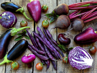 purple vegetables on wooden background - eggplant, cauliflower, green beans, cherry tomatoes, basil, onion, cabbage, sweet pepper