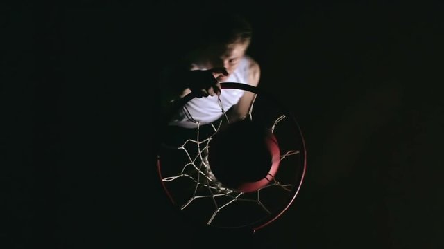 Directly above view of athlete in white uniform throwing ball into basketball hoop in slow motion