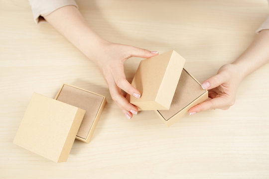 Female hands opening carton box, flat lay. Top view on woman holding and unblocking package with some product, free space. Delivery service. online shopping, parcel getting concept