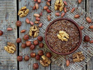 flax seeds in bowl and walnuts, hazelnuts, peanuts. selective focus