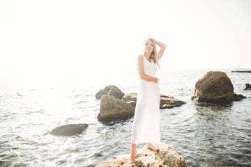 portrait of young woman posing near sea, wearing a dress