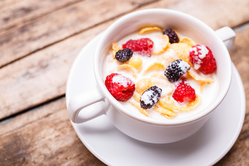 Close up image of corn flakes with berry and milk