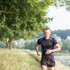Fototapeta premium Young athletic man jogging in morning park