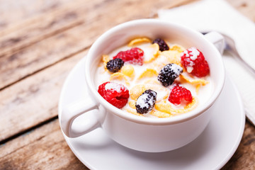 Close up image of corn flakes with berry and milk