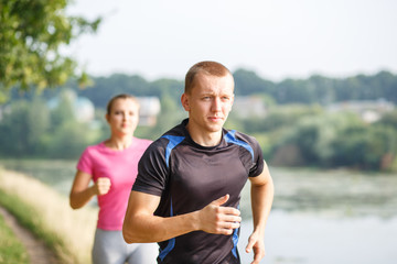 Young athletic people jogging outdoor near pond