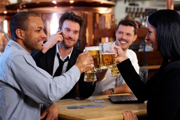 Young office workers toasting with beer at pub