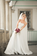 Fototapeta premium Beautiful bride with wedding bouquet posing in old city