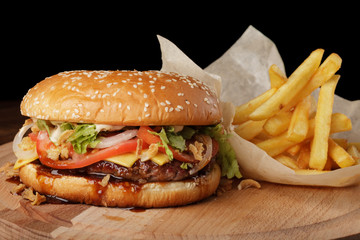 Cheeseburger (burger) with french fries and sauce. Hamburger on a brown wooden background