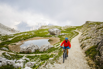 Fototapeta premium Mountain Bike cyclist riding single track on rocks healthy lifestyle active vacation in Italian Alps