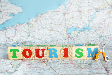 Tourism word write on wooden cube on map background.