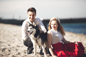 Naklejka na ściany i meble Portrait of a happy couple with dogs at the beach