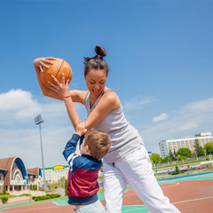 Naklejka premium Mom and little boy son playing basketball
