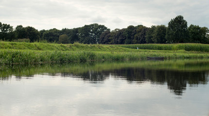 Fototapeta na wymiar Dutch river de Berkel with small boat corn field. Achterhoek. Ge