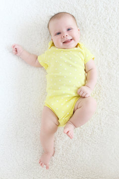 Happy smiling 2 months baby girl in yellow bodysuit
