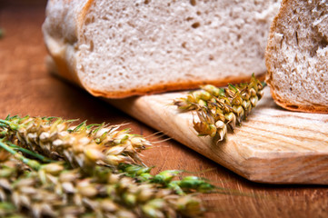 Fresh bread and wheat on wooden background