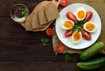 Boiled egg and fresh tomato, black bread - light diet breakfast. The top view