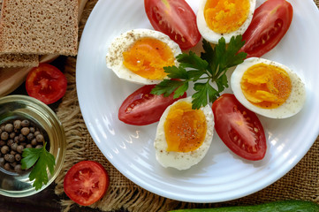 Boiled egg and fresh tomato, black bread - light diet breakfast.