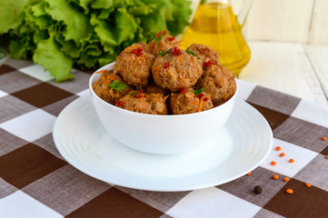 Meat balls with chilli and herbs in a white bowl closeup.
