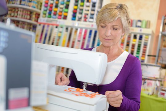 Lady using sewing machine in craft shop