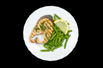 plate of grilled salmon steak isolated on black background