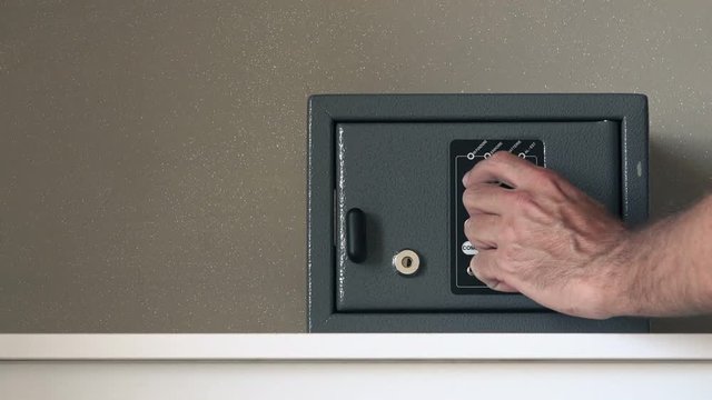 Man opening safety deposit box in hotel, hand typing security code and unlocking the door or the safe.