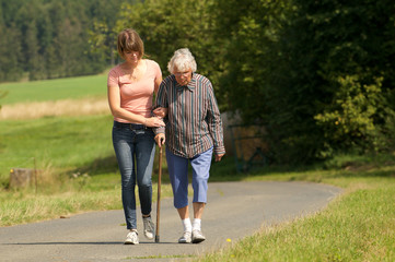 Obraz premium Junge Frau hilft Seniorin beim laufen