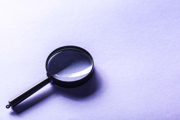 Magnifier on blue background close up