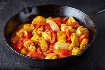 Jalfrezi chicken traditional Indian culture fried spicy meat and vegetables healthy food dish in cast iron pan on vintage wooden table background.