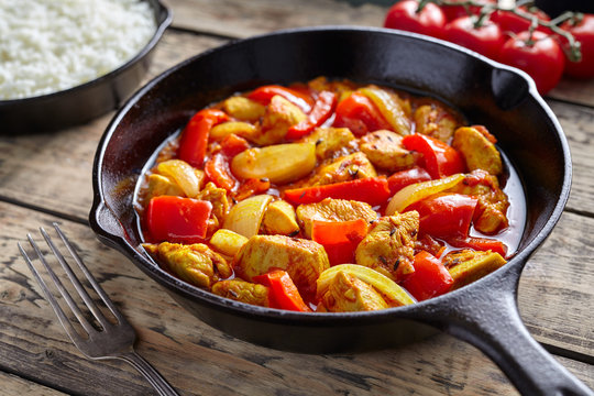 Chicken jalfrezi healthy traditional Indian culture restaurant curry spicy fried meat with chilli and vegetables, tomatoes, pepper, onion, asian food in cast iron pan on vintage table background