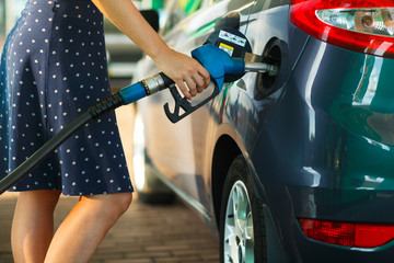 Woman fills petrol into the car at a gas station